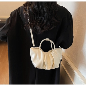 Detail of off-white pleated cloud bag with round handle on a black coat back view