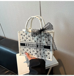 Detail of cream tote bag with black bow prints and Fashion Bag banner ornament