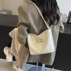 Chic cream white PU leather shoulder bag with decorative bow on stylish khaki blazer