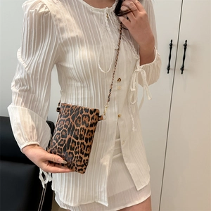 Chic leopard print crossbody bag with gold chain strap on a white pleated dress