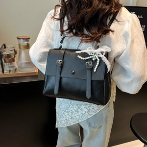 Fashionable black faux leather backpack with metallic buckles and pearl bow charm