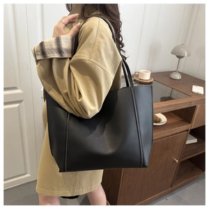 Close-up of a large black matte leather tote bag with vertical stitching on shoulder