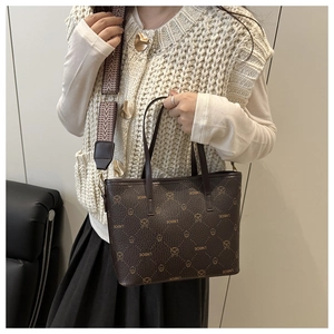 Detailed view of brown leather bucket bag featuring LNBOE bear print and wide woven strap