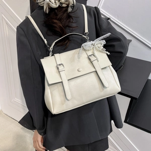 Chic beige leather backpack with decorative pearl strap shown on model in grey blazer