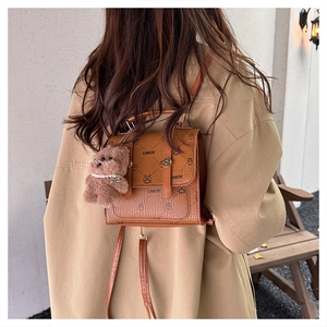 Brown retro backpack detail featuring cartoon prints and a cute plush bear pendant accessory