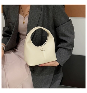 Detailed close-up of cream-white leather half-moon handbag featuring dual zipper closure