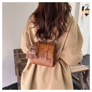 Detail of vintage brown backpack featuring cartoon rabbit prints and a plush bear pendant