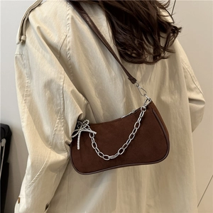 Sac sous le bras en daim marron avec chaîne argentée et nœud porté par un mannequin
