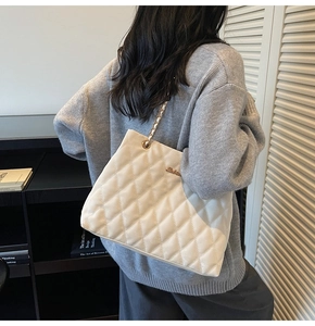 Close-up of white quilted tote bag featuring fine stitching and gold chain shoulder strap