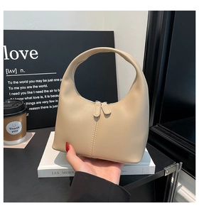 Close-up of beige minimalist handbag with double zipper and sleek matte leather texture