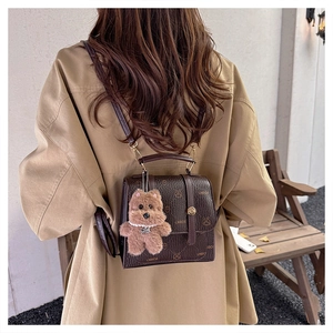 Detail of dark brown retro monogram backpack with a cute plush bear pendant on a model