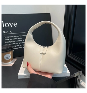 Detail of creamy white leather handbag with dual silver zippers and vertical stitching