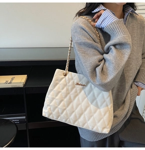 Detailed view of white quilted padded crossbody bag with elegant gold chain strap