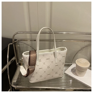 Detail of white bucket bag with cartoon animal patterns and a striped woven strap