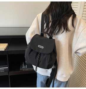 Detail of black nylon backpack featuring a drawstring closure and logo patch