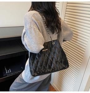 Detailed close-up of a black quilted leather tote bag featuring a gold chain strap