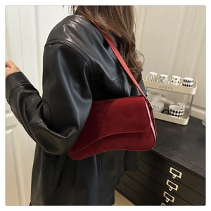 Detail of burgundy faux suede shoulder bag with unique asymmetrical curved bottom design