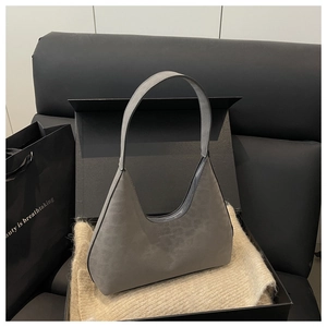 Detail of gray suede half-moon underarm bag inside a gift box with embossed logo