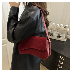 Detail of the wavy flap design and matte suede texture on a vintage burgundy shoulder bag