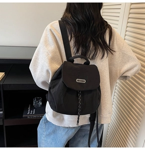 Detail of black nylon mini backpack with flap closure and metal logo branding