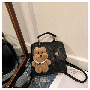 Detail of black mini backpack with LNBOE embossed patterns and brown plush bear charm