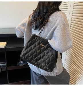 Close-up of black quilted chain tote bag with classic diamond stitching and metal logo