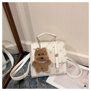 Detail of white embossed leather handbag with LNBOE logo and plush bear charm decoration