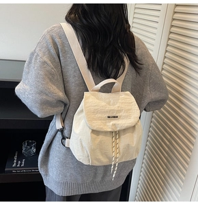 Detail of a beige mini nylon backpack showing the stylish pleated texture and rubber logo