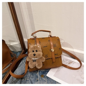 Detailed view of brown lychee-textured small square bag with cute rabbit print and teddy bear charm
