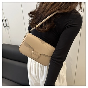Détail du sac à épaule en cuir beige avec chaîne dorée et fermoir à boucle