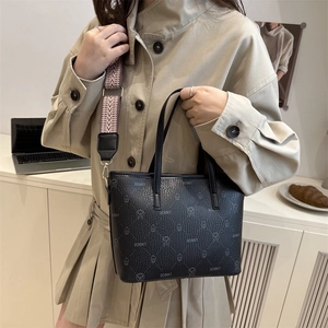 Minimalist black leather bucket bag with bear print and geometric woven shoulder strap