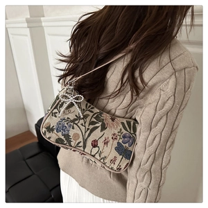 Detail of floral jacquard baguette bag with pearl bow charm on model's shoulder