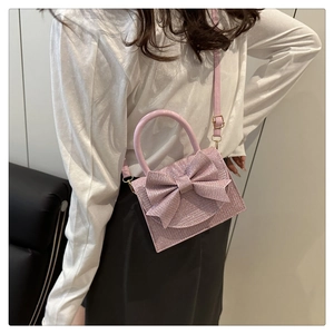 Pink glitter mini evening bag featuring a large bow and adjustable crossbody strap