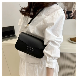 Sac bandoulière chic en similicuir noir avec bandoulière chaîne dans un décor lifestyle