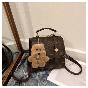 Detail of dark brown textured leather backpack with animal patterns and plush dog charm
