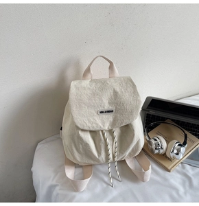 Detail of cream nylon backpack with You Ji Bear logo and drawstring closure design