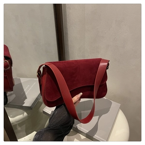 Close-up of deep red suede crossbody bag with vintage flap design and leather strap