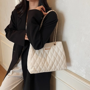 Minimalist beige quilted tote bag with chain strap and gold logo for daily commute