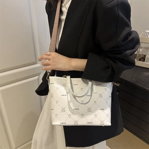 White leather bucket bag with bunny print and patterned strap worn with black suit
