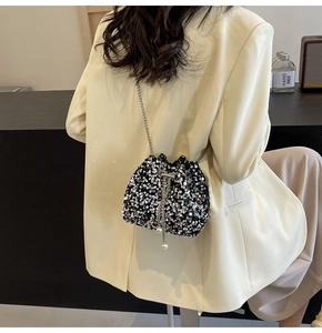Detail of silver sequined bucket bag with pearl drawstring and metal chain strap