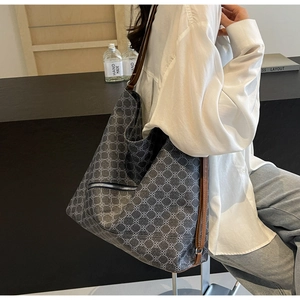 Detail of grey tote bag with white floral pattern and brown leather straps worn by model