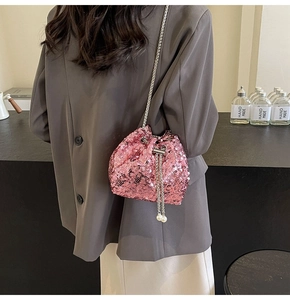 Detail of pink sequin bucket bag featuring silver chain and elegant pearl drawstring accents