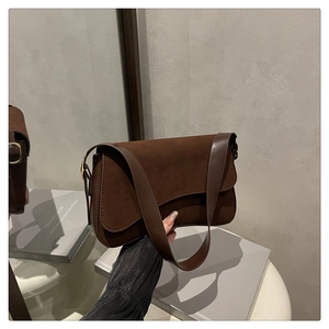Detailed close-up of dark brown suede and smooth leather texture on a vintage baguette bag