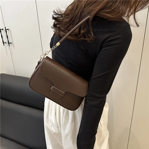 Sac à bandoulière minimaliste en cuir marron avec chaîne dorée porté par un mannequin