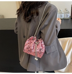 Close-up of pink sequin bucket bag featuring silver chain and white pearl drawstring detail