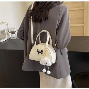 Détail du sac crème avec fermoir papillon et accessoire de charme en forme de nuage