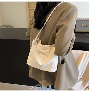 Détail d'un sac cabas en nylon blanc avec nœud et tissu texturé porté à l'épaule