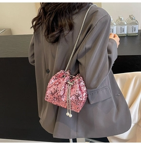 Close-up of pink sequin bucket bag with silver chain strap and pearl drawstring detail