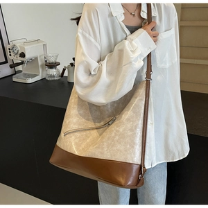 Detail of minimalist large tote bag with cream cracked texture and brown leather patchwork