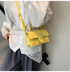Side view of model wearing a bright yellow crossbody bag with fashion print and flap cover